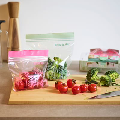 Two IKEA ISTAD resealable bags, one with green leaf designs, the other with pink floral patterns. Both are transparent with double seals.