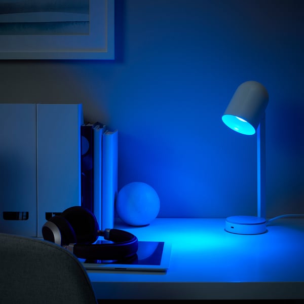 Modern desk setup with KAJPLATS smart lamp, laptop, headphones, and speaker.