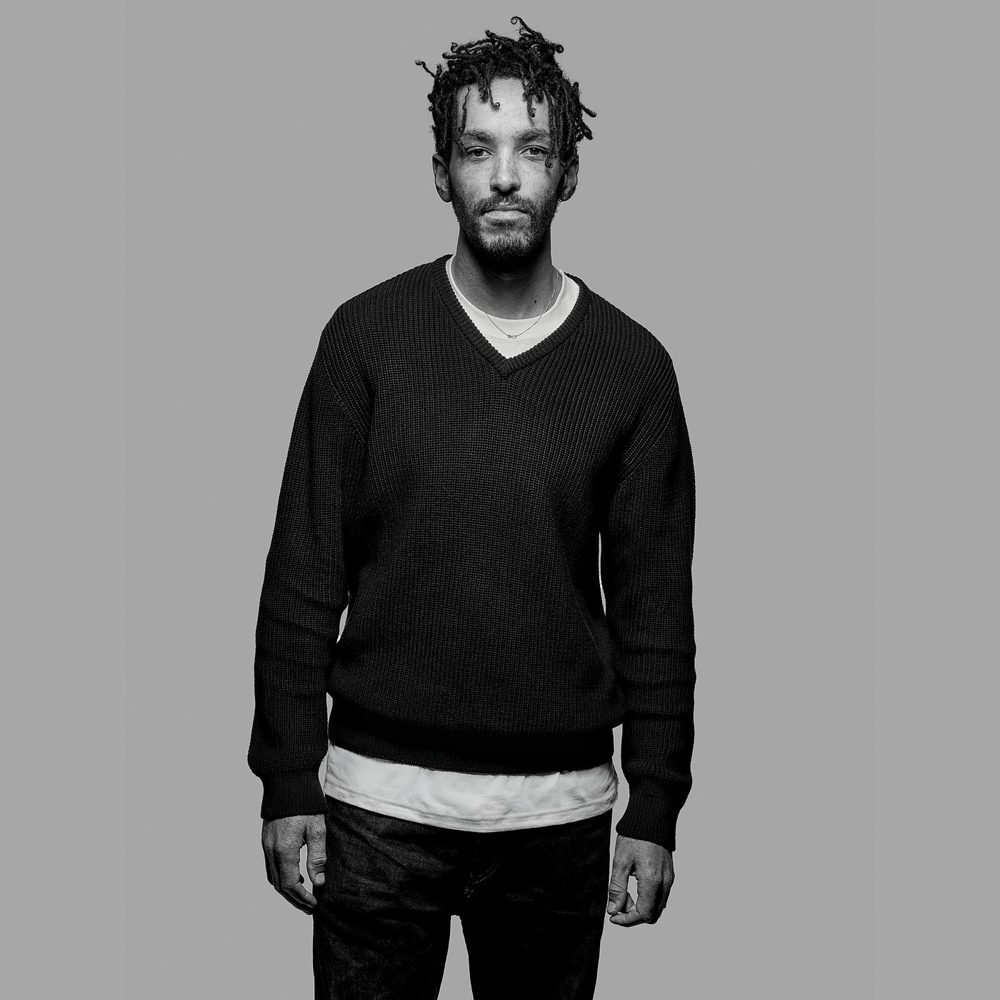 Black and white portrait of the designer wearing a sweater and jeans.