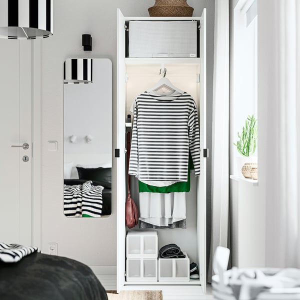 Open closet with striped shirt hanging, storage boxes below, and mirrors beside.