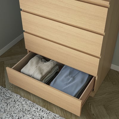 An ikea MALM chest in light oak wood. Its rectangular, with four smooth drawers, and a minimalist design.