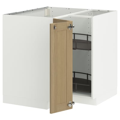 A white METOD kitchen cabinet with a light oak door slightly open, revealing black shelves inside.