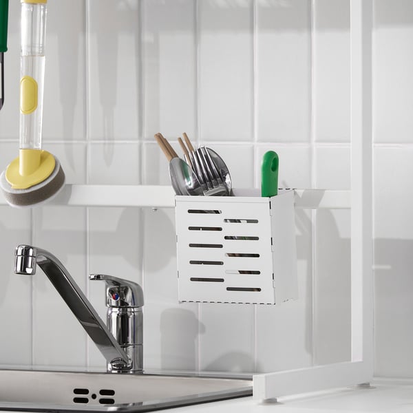 Kitchen sink with a white SKYGGFISK dish drainer, holding utensils and a green sponge on the tap.