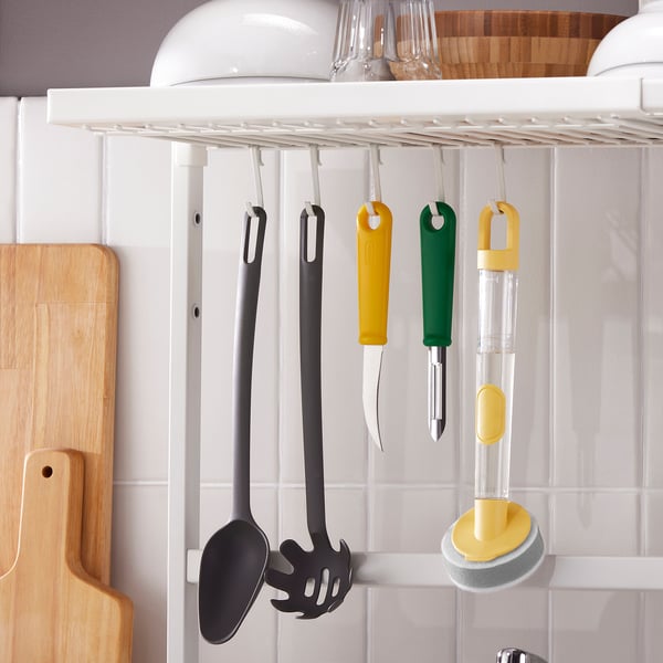 Kitchen organiser hangs utensils on shelf, keeps counter neat. Adjusts for varied sink sizes.