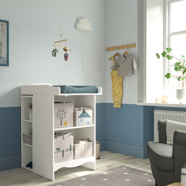 Baby nursery with SMÅGÖRA changing table, blue walls, plant, and grey chair.