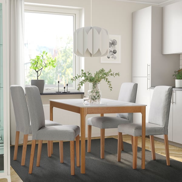TRÖDEN dining set with ceramic top, wooden legs, grey chairs, pendant light, plants, kitchen. Minimalist space.