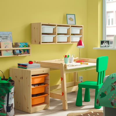 Yellow kids room with wooden TROFAST storage, green chair & lamp, books & toys on shelves.