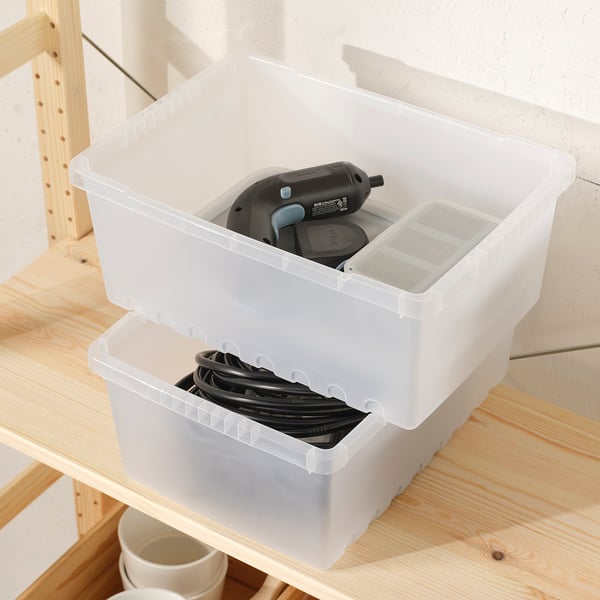 Two plastic storage boxes on shelf. Front holds cables, back has drill and charger. Rectangular, snap-lid design.