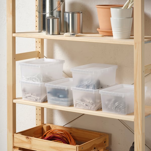 Shelf with transparent UPPSNOFSAD boxes, larger than others, storing various items. Includes metal containers and wooden crate with cords.