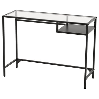 A black VITTSJÖ desk with a glass top and metal frame. It has an open shelf for storage.