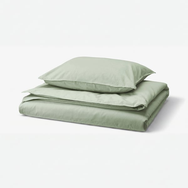 Mehak žajbljevo zelen komplet posteljnine, vključno z prevleko za odejo in prevleko za blazino, lepo zložen. Izdelan iz recikliranega bombaža. Minimalističen, čist dizajn.
