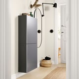 Sodobna siva stenska omara, minimalističen dizajn, z dvema vratoma, pleteno košaro in stensko lučjo v minimalistični sobi.