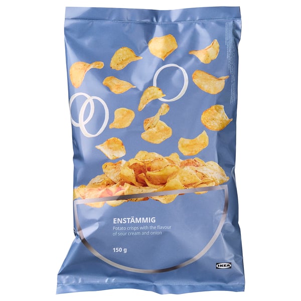 Modri paket krompirjevega čipsa ENSTÄMMIG z okusom kisle smetane in čebule, prikazan s čipsom, ki pade in se nabere. Blagovna znamka IKEA, 150g.