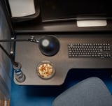 Sodobna črna miza z monitorjem, tipkovnico, svetilko in posodo za prigrizke.