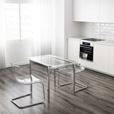 Sodobna kuhinja z majhno stekleno mizo GLIVARP in 2 prozornima stoloma v bližini pečice. Eleganten, minimalističen dizajn.