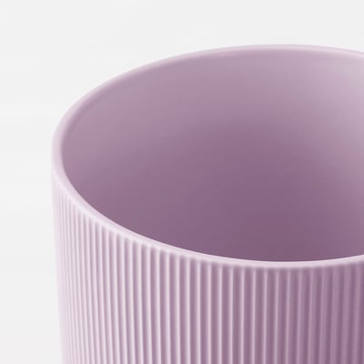 Bližnji posnetek gladkega, pastelno vijoličnega lončenega kozarca z navpičnimi utori, ki prikazuje teksturirano površino in fino izdelavo.