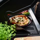 Litoželezni GRILLTIDER drži pico z zelenjavo na žaru. Ročaji omogočajo enostavno dvigovanje.