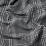 Bližnji posnetek temno sivih tartan zaves HÄGGVECKMAL, ki prikazuje fino tkanje in teksturirano tkanino.