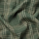 Bližnji posnetek temno zelenih tartan zaves z zapletenimi belimi linijami, ki prikazujejo visokokakovostno teksturo tkanine.