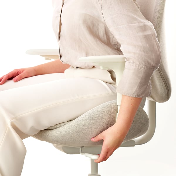 Oseba, ki prilagaja ergonomske pisarniške stole, globino sedeža, zagotavlja udobje in podporo.