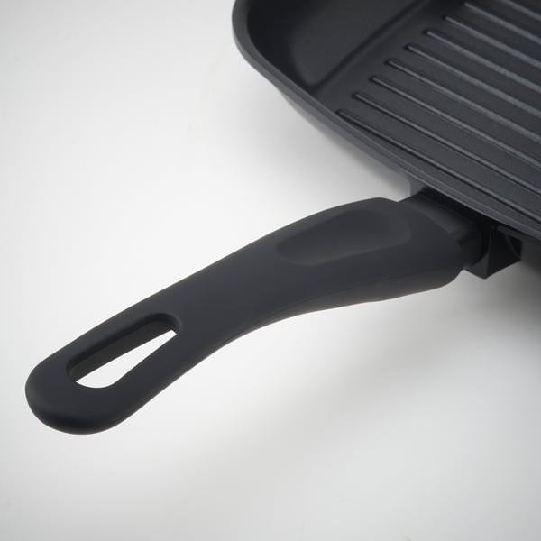 Črna ponev za žar z ergonomskim ročajem na beli površini. Nelepljivo, enakomerno toploto, enostavno rokovanje.