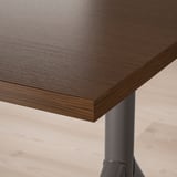 Bližnji posnetek temne lesene mize z vidnim drobnim zrnom in elegantnim, gladkim zaključkom.