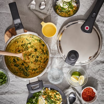 Sivi lonec IKEA 365+ s čičerikim curryjem, okraski, limeto in pripomočki na prtu.