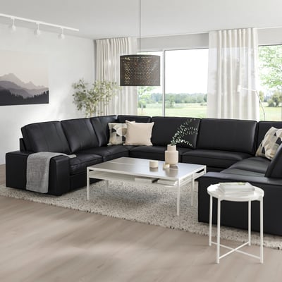 Moderna dnevna soba z velikim črnim kavčem KIVIK v obliki črke L, belo mizico in velikim oknom, ki ponuja udoben in eleganten prostor.