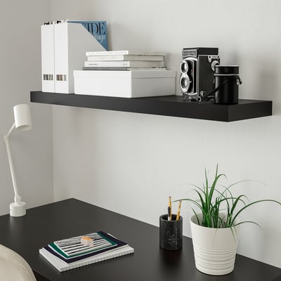 Poiščite elegantno stensko polico bLACK LACK, ki vsebuje bele knjige in starinsko kamero, v kombinaciji z mizo bLACK z zloženim zvezkom in sodobno svetilko.