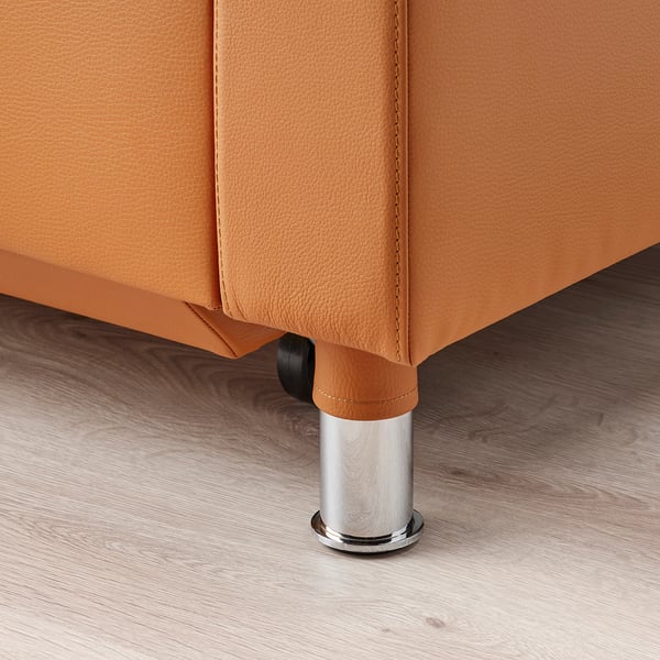 Bližnji posnetek oranžne usnjene noge kavča, gladke teksture in kromirane obdelave.