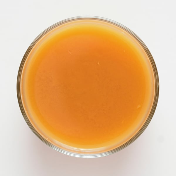 Oranžno obarvan smoothie v steklu, kremasta tekstura, narejen iz sadja in zelenjave.