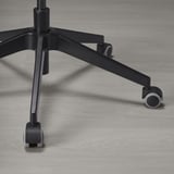 Črno podnožje pisarniškega stola s petimi kolesi, dvema vidnima in eno osrednjo nogo, ki prikazuje robustno, ergonomsko obliko za stabilnost in mobilnost.