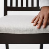 Bližnji posnetek stola NÄSINGE, ki prikazuje mehki, oblazinjeni sedež in trden lesen okvir, ki poudarja kakovost in udobje.