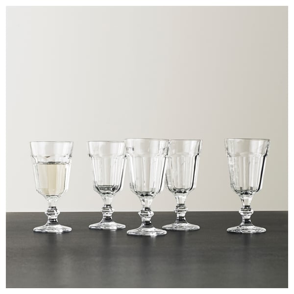 Pet prozornih kozarcev za vino POKAL, vsak klasičnega, elegantnega dizajna, lepo razporejenih na temni površini.