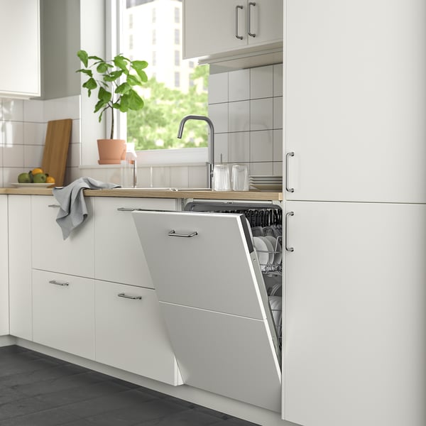 Sodobna kuhinja s tankim pomivalnim strojem ikea RENGÖRA, belimi omarami, sivo brisačo in steklenimi predmeti.