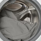 Odprite pralni stroj s temnimi hlačami v notranjosti, s poudarkom na enostavnosti nalaganja in razkladanja.