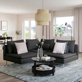 Sodobna dnevna soba z velikim črnim kavčem SÖDERHAMN, elegantno mizico, elegantno visečo svetilko in velikimi okni s pogledom na mesto.