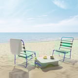 Dva zeleno-bela črtasta ležalnika za plažo STRANDÖN z majhno belo mizico na peščeni plaži, ocean v ozadju.