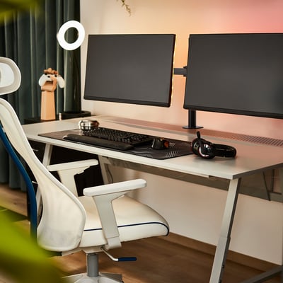 Dvojni monitor s črnimi rokami STUBBERGET, bel ergonomski stol za udobje.