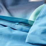 Detailný záber na modrú obliečku na paplón so zipsom, ktorý ukazuje jeho ľahko použiteľnú funkciu zapínania.