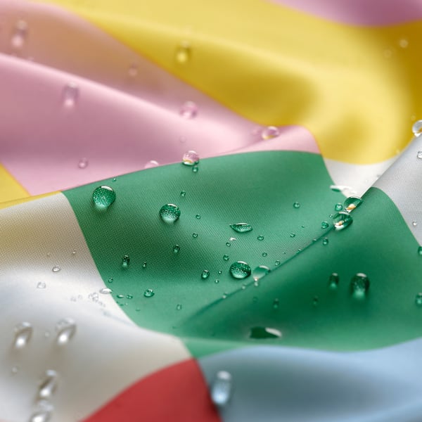 Detailný záber vody na viacfarebnom sprchovom závese, ktorý ukazuje jeho vodoodpudivú kvalitu.