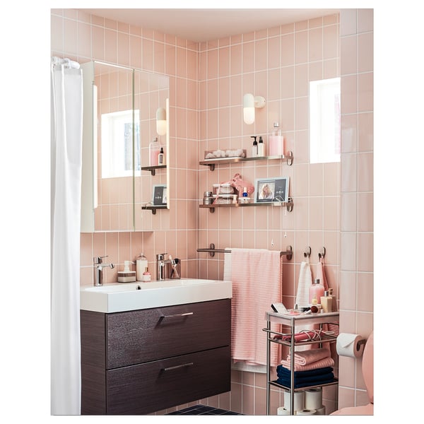 Moderná kúpeľňa s ružovou dlažbou s dreveným umývadlom, bielym umývadlom, kovovými doplnkami a policami.