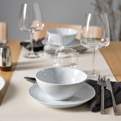 Minimalistická biela porcelánová miska na tanieri; Poháre na víno, príbor, servítky.