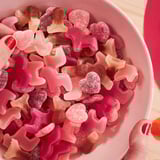 Miska farebných gumových cukríkov v tvaroch hviezd, srdiečok a losov s odtieňmi červenej, ružovej a oranžovej.