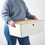 Osoba nesúca obdĺžnikový úložný box s vekom.