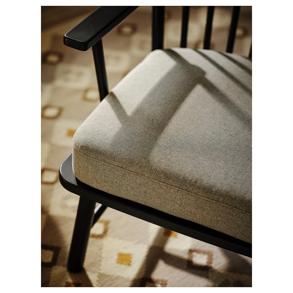 Moderná stolička: PERSBOL, čierny kovový rám, béžový vankúš, zakrivené operadlo, pohodlné sedadlo.