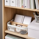 Drevená polica s úložným košom RISATORP s notebookom, notebookom a perami, ideálna na organizovanie a prepravu drobností.