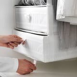 Osoba vytiahne biely organizér SKUBB z police, ukáže rukoväť a priehradky na uloženie.