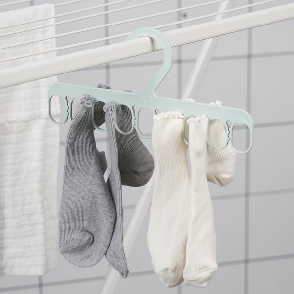Vešiak s viacerými pútkami drží sivé a biele ponožky na sušenie, čo ukazuje jednoduchú organizáciu.