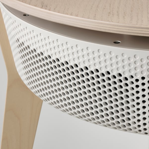 Detailný záber na moderný, elegantný biely stôl čističky vzduchu. Kruhový perforovaný dizajn, štýlová noha zo svetlého dreva.